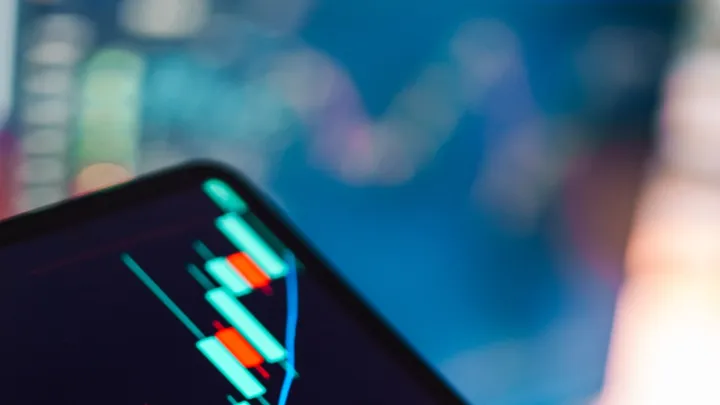A close-up of green and red candlestick charts on a financial market display