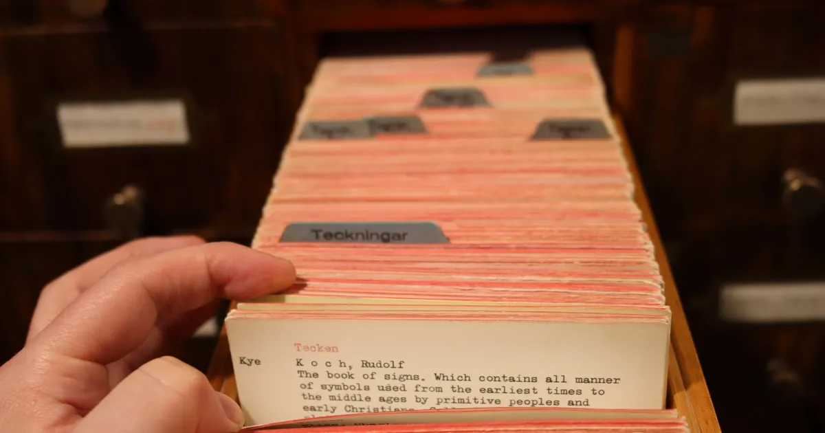 A library card catalog with rows of small wooden drawers