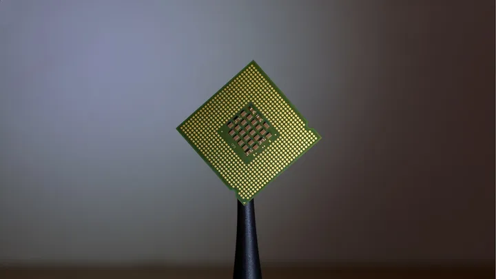 A semiconductor chip balanced on a fingertip, representing advanced processor design