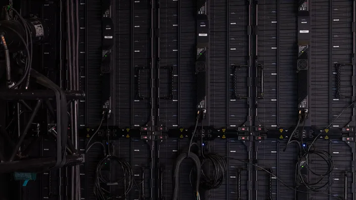Rows of illuminated server racks inside a large data center hall