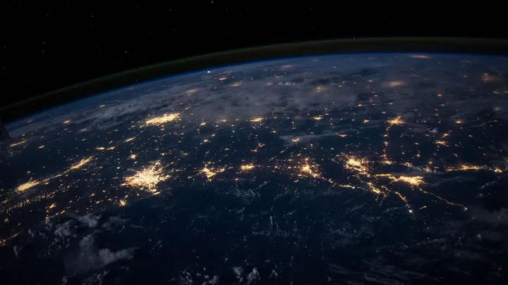 The curved edge of Earth at night seen from space, with city lights glowing