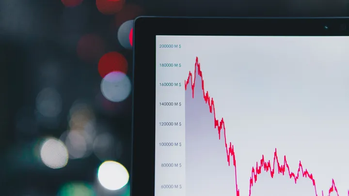 A downward-sloping financial chart on a dark screen, representing a falling stock price
