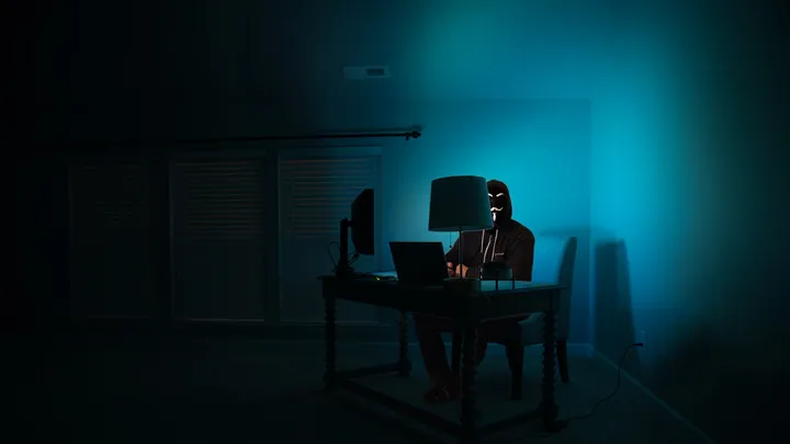 Dark room with multiple monitors showing code