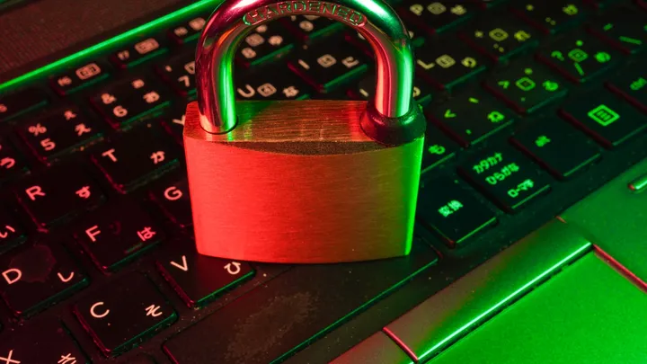 A red padlock resting on a laptop keyboard, representing a broken confidentiality boundary