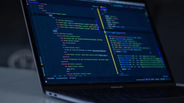 Laptop displaying code under blue lighting