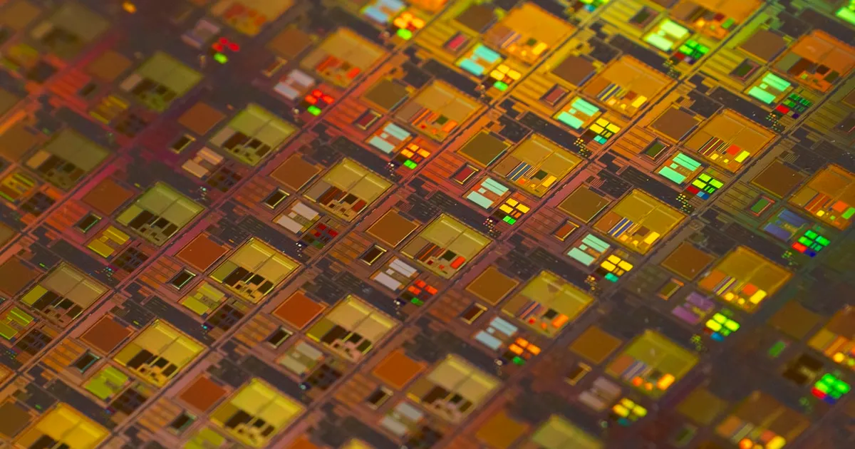 A silicon wafer patterned with rows of semiconductor dies under bright light