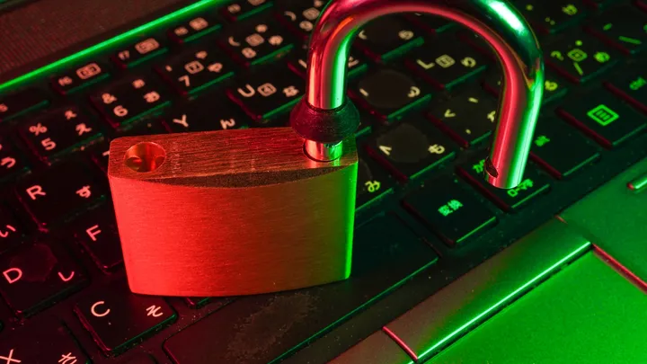 An open padlock resting on a laptop keyboard