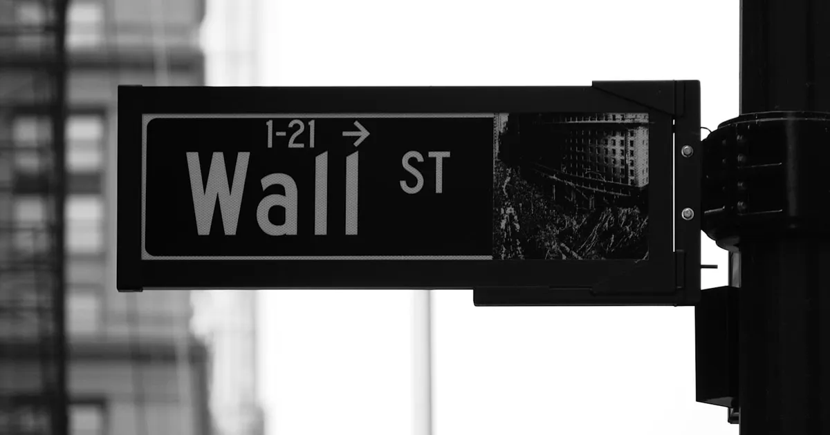 A Wall Street street sign against city buildings